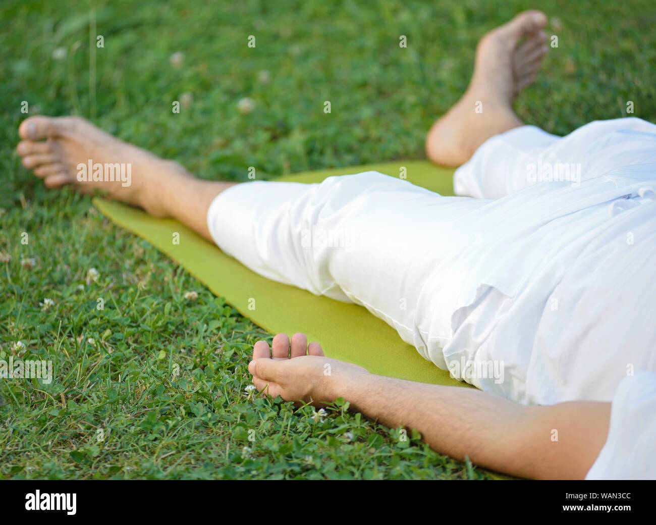 Man Lying on Back on Grass Yoga Practice Stock Photo