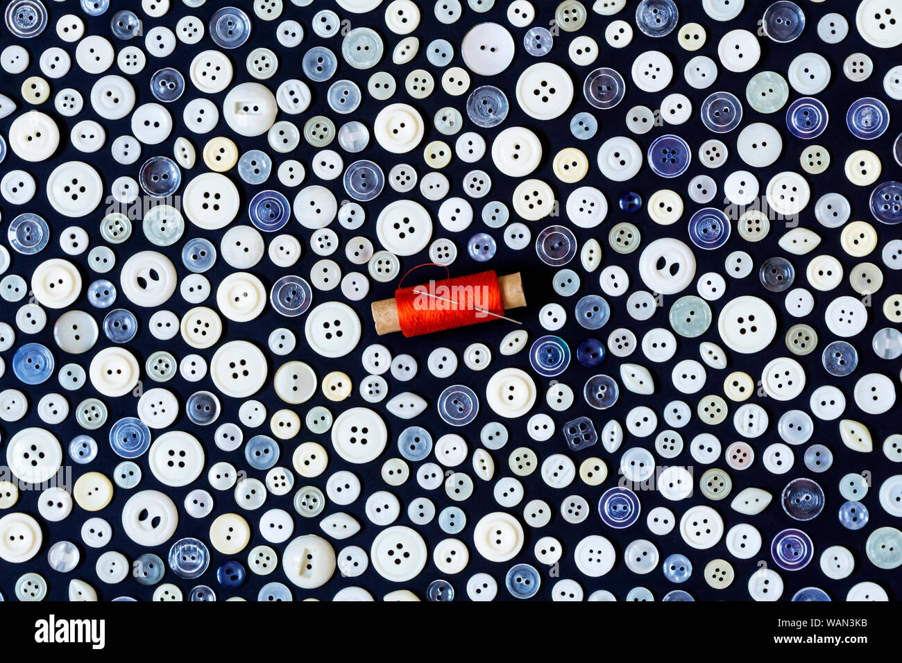 background - different light buttons and reel of red thread with needle ...