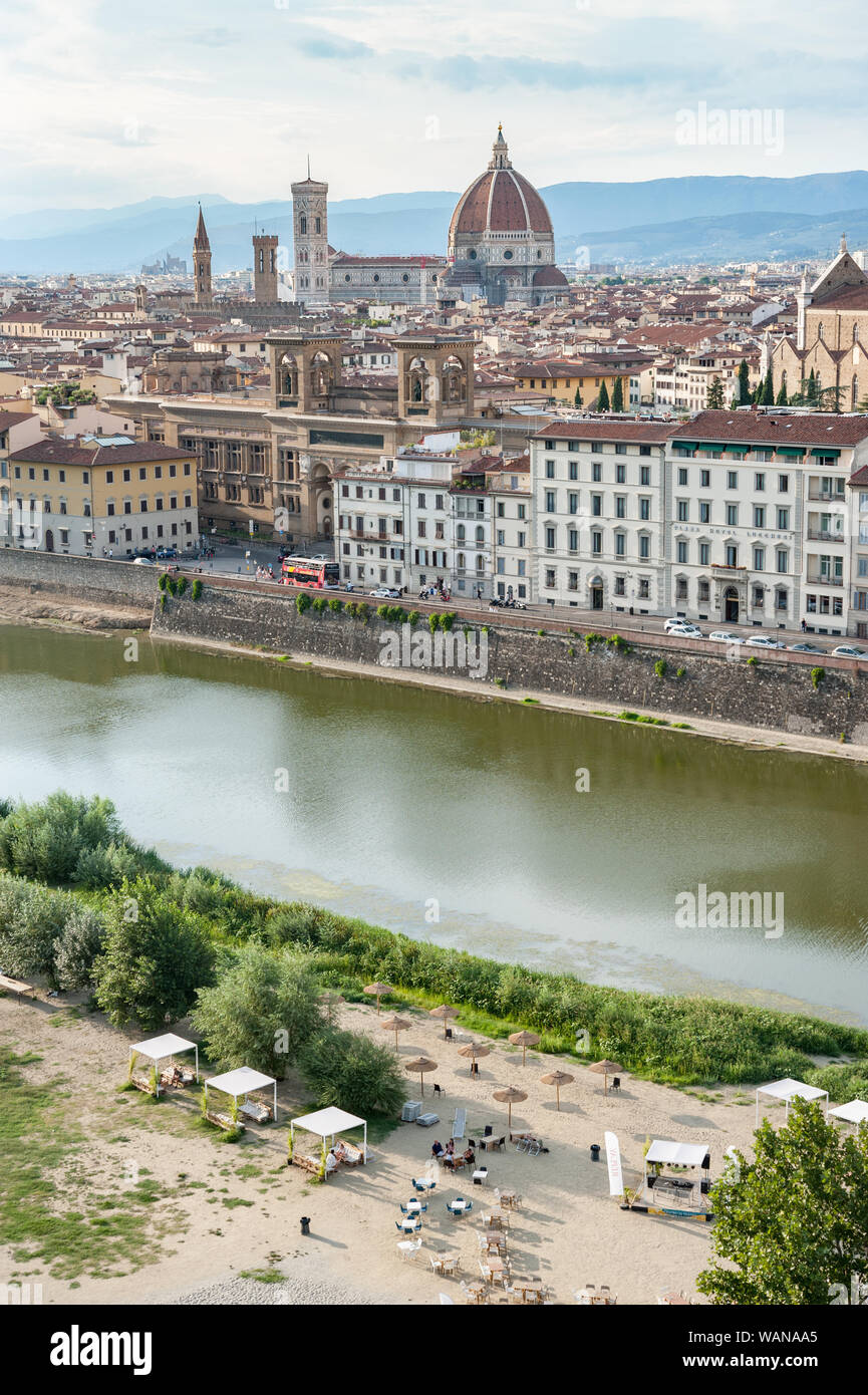 Sunbed and sunshades on the Arno river urban beach. Florence cityscape with Basilica Santa Maria del Fiore, Giotto’s tower, National Central Library. Stock Photo