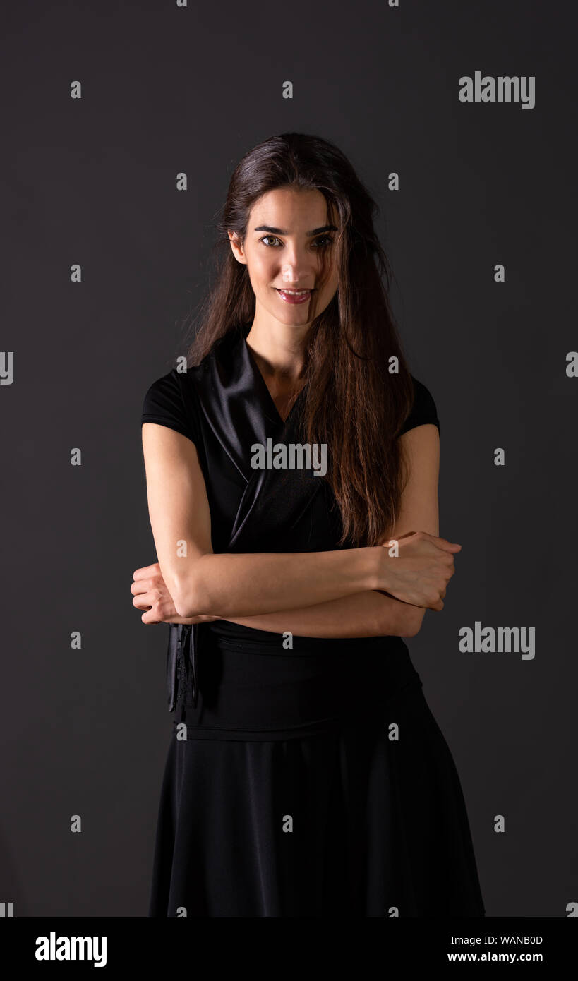 A beautiful smiling young woman in an elegant black dress standing in ...