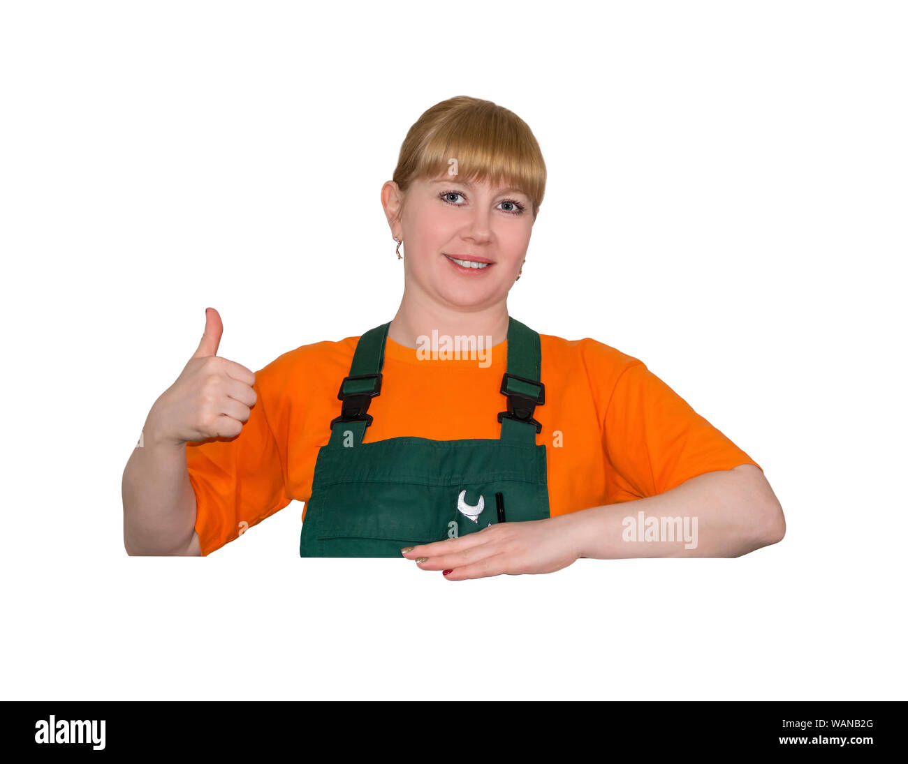 young woman in a work overalls holds thumb up, standing over empty space without inscriptions, isolated on white background Stock Photo