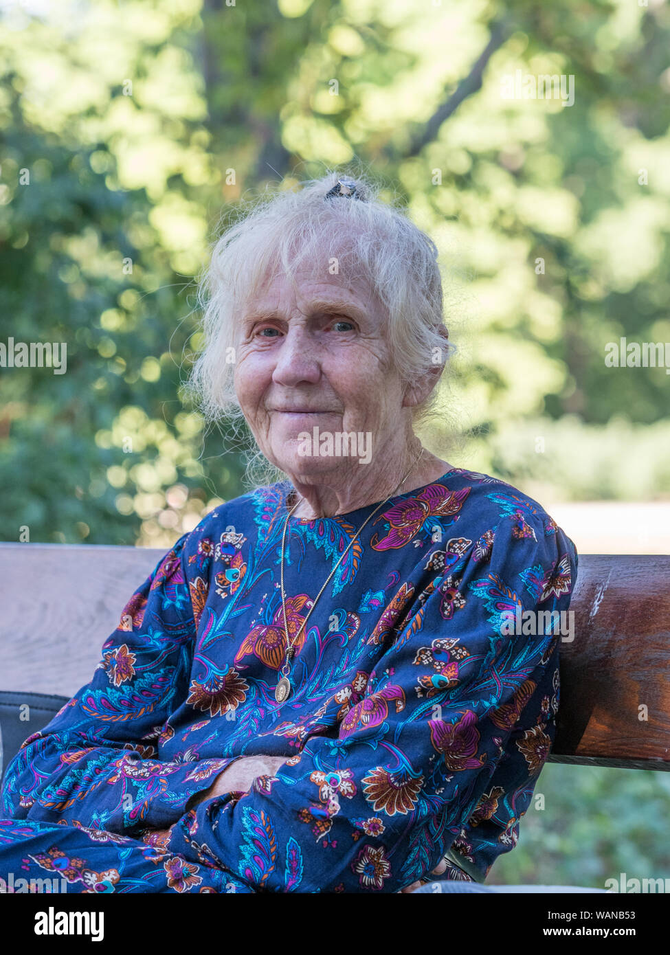 An elegantly dressed, elderly woman is sitting on a park benchis sitting on a park bench. Poland. Stock Photo