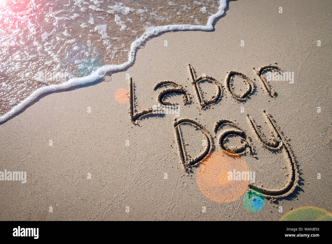 Labor Day message handwritten on the smooth sand of an empty beach with ...