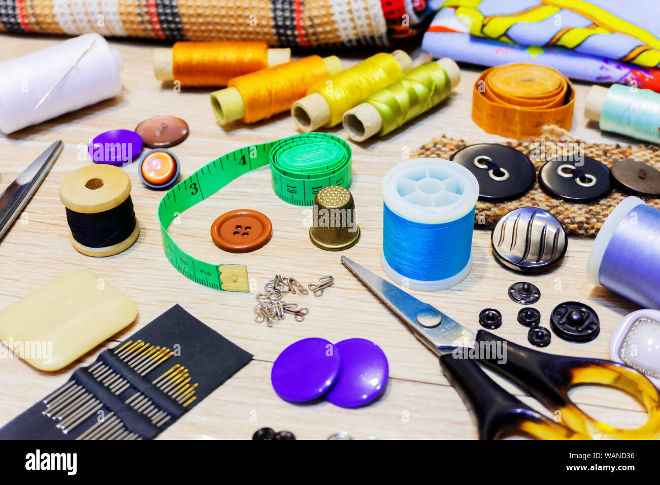 various accessories for sewing and needlework lie on the table close-up with blurred background and foreground Stock Photo