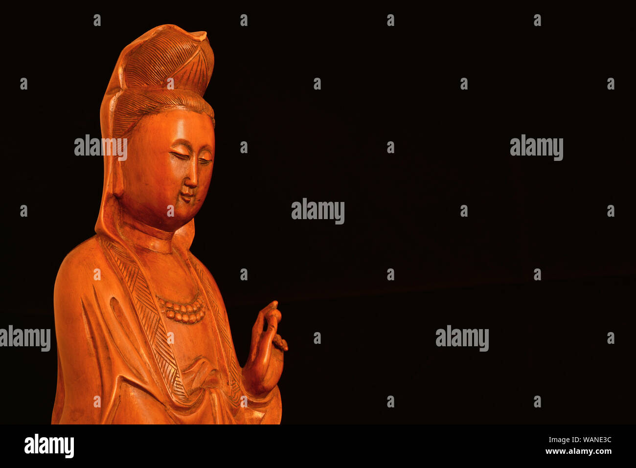 Buddhist religion and meditation. Kannon or Guanyin, the Goddess of Mercy, wooden statuette on black background (with copy space) Stock Photo