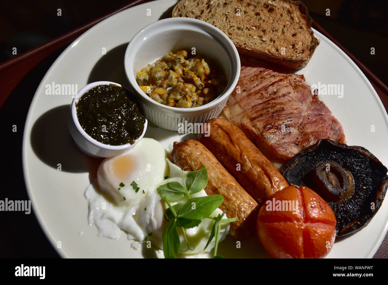 Welsh cooked breakfast, poached egg, laver bread, cockles, toast, sausages, bacon, tomato, mushroom, watercress Stock Photo