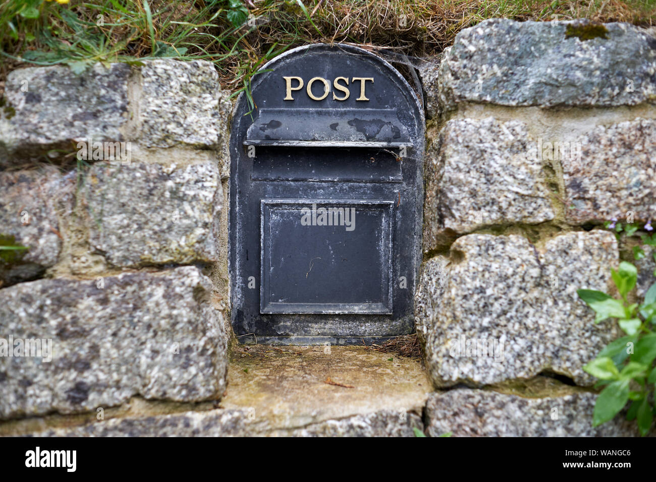 There is an old English metal mailbox built into the stone wall. Stock Photo