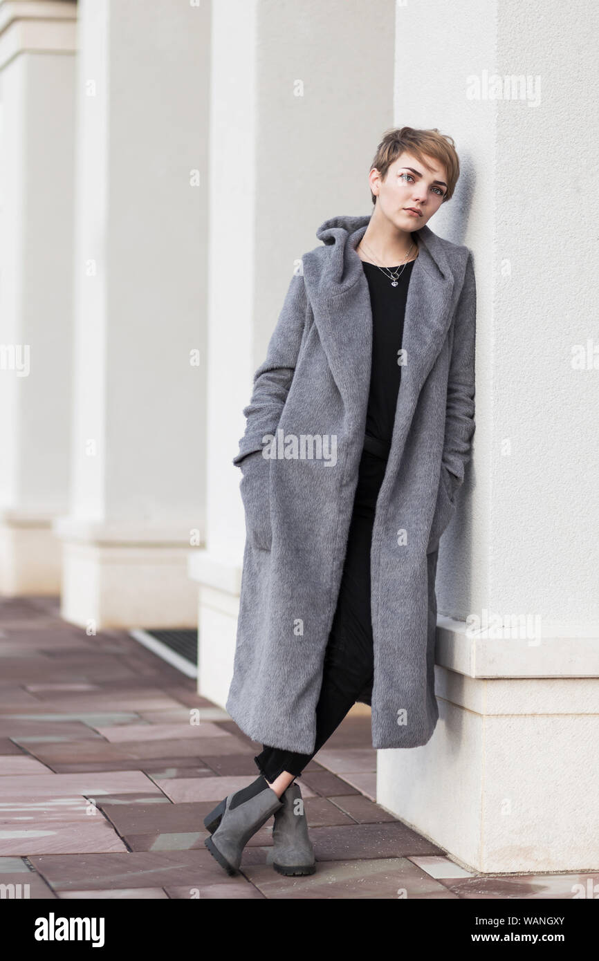 Stylish woman with short haircut in gray coat on white background Stock Photo