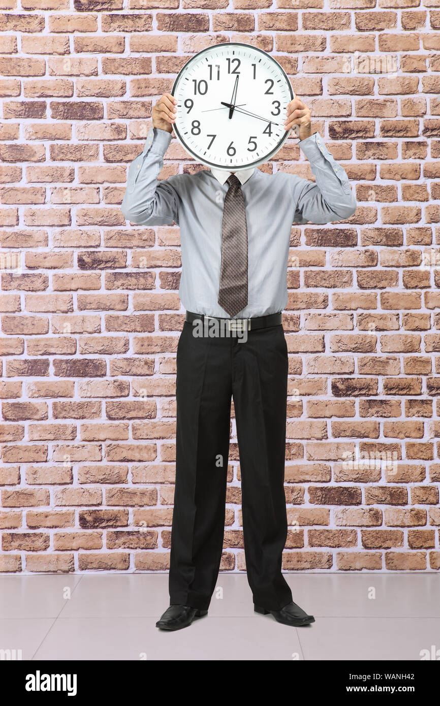 Businessman holding a clock in front of his face Stock Photo