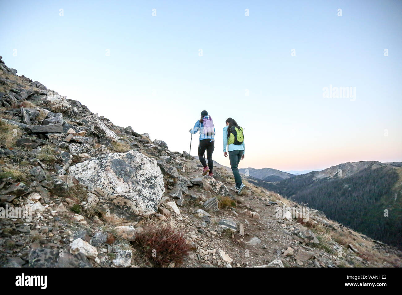 Two women trail runners push uphill in a Rocky Mountain early morning Stock Photo