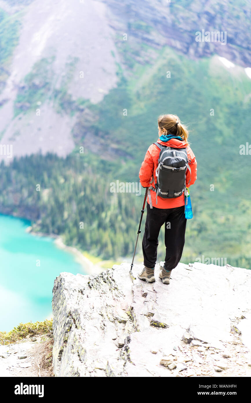 Hiker is standing on a cliff looking at the lake in GlacierNP, Montana Stock Photo