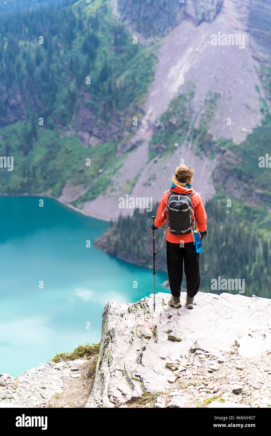 Hiker is standing on a cliff looking at the lake in GlacierNP, Montana Stock Photo