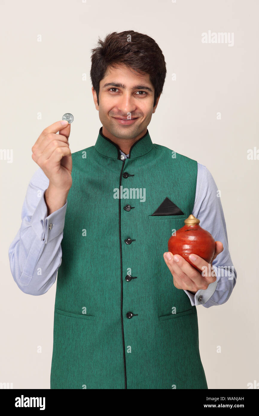 Young man holding a coin with a piggy bank Stock Photo