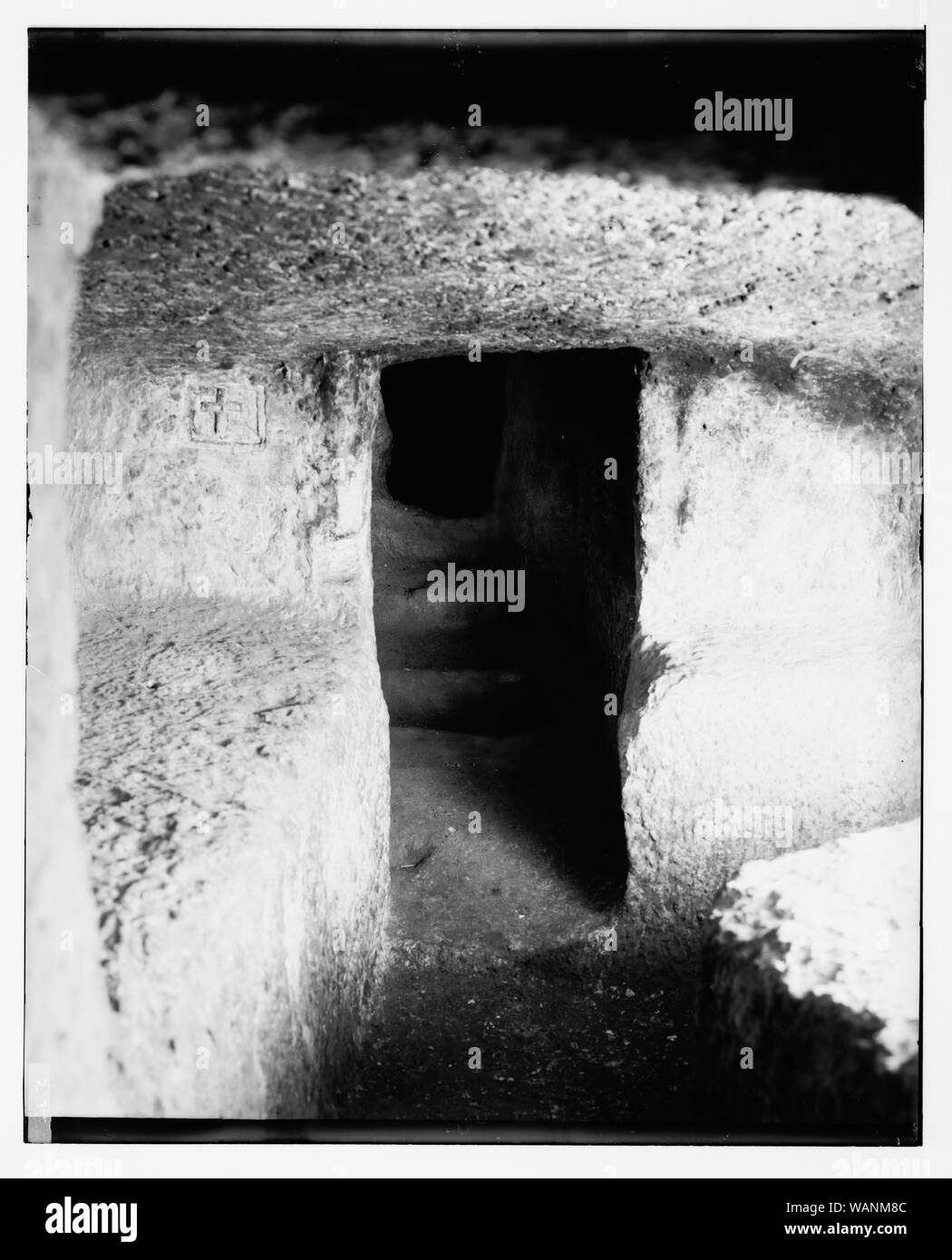 Cross carved onto door of stone passageway Stock Photo