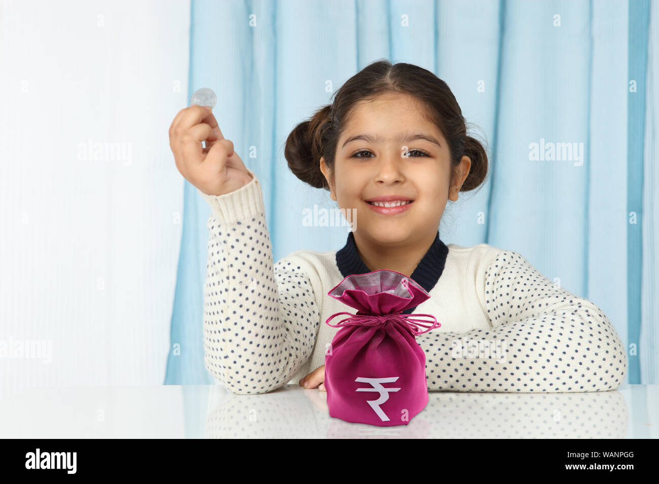 Girl holding a coin and smiling Stock Photo