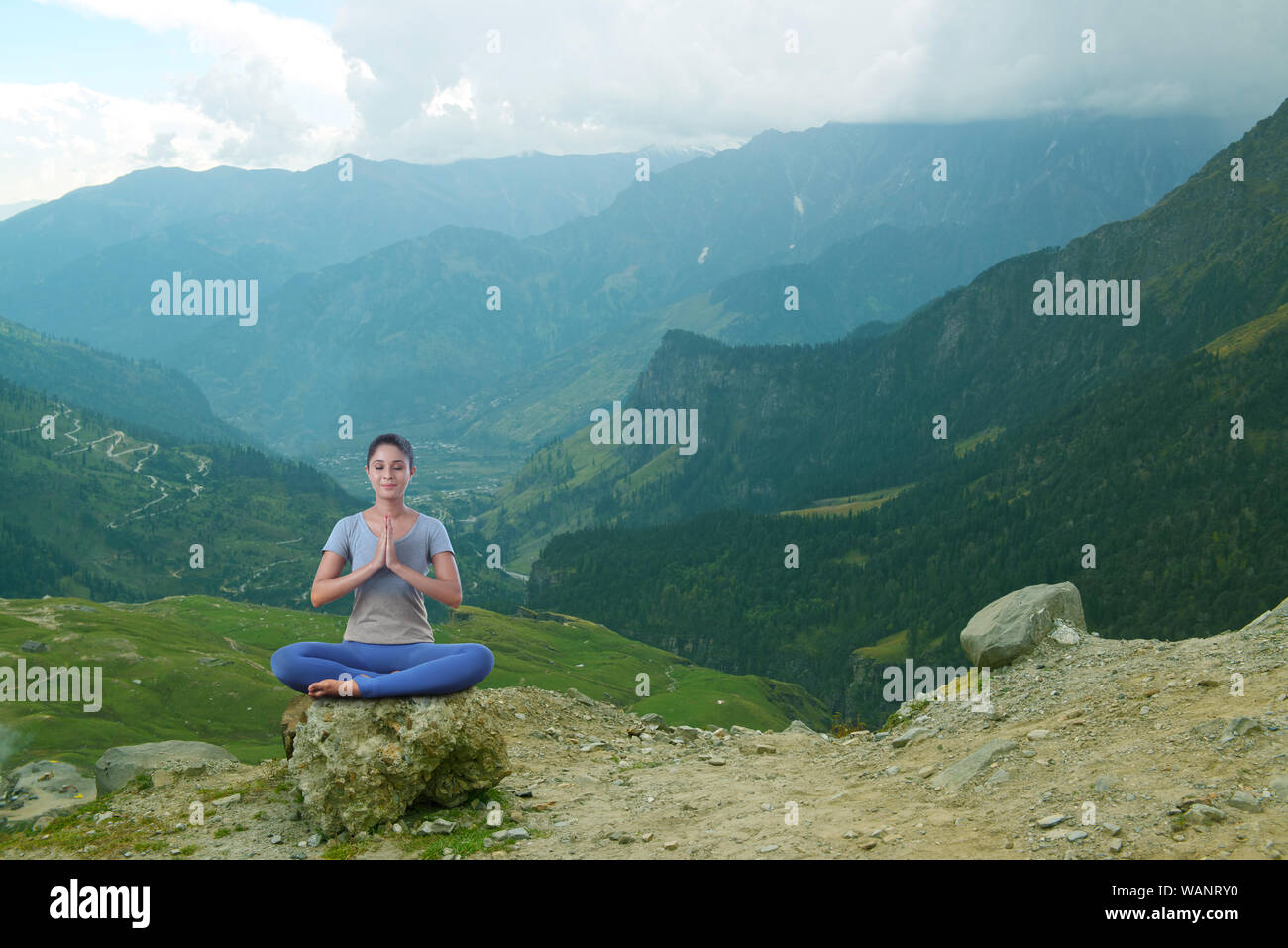 Young woman practicing yoga sitting on rock Stock Photo