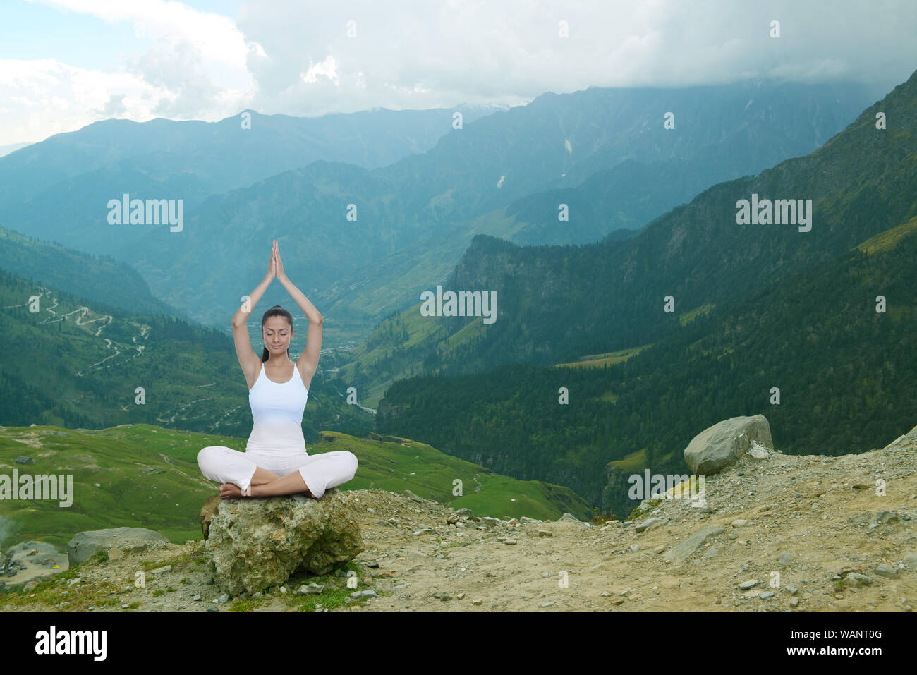 Young woman practicing yoga sitting on rock Stock Photo