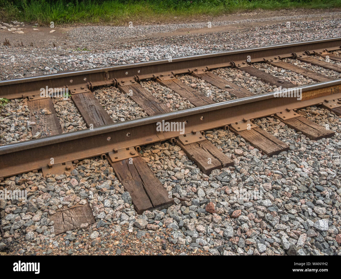 Close-up of a section of railroad tracks, with rails and ties (sleepers) set in stone ballast running at an angle in the USA. Stock Photo