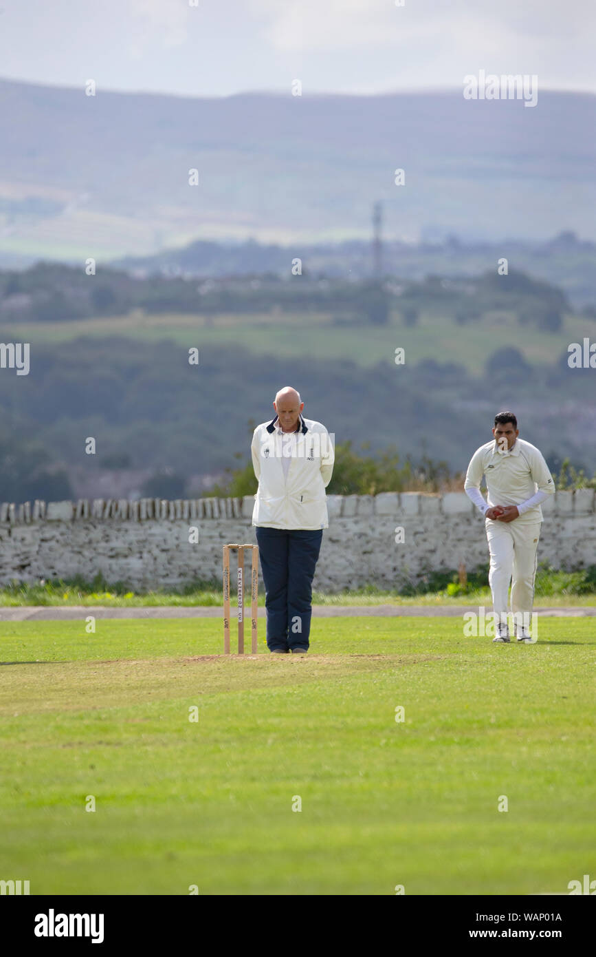 Umpire officiating in a village cricket match on a Saturday afternoon in summer in West Yorkshire, England Stock Photo