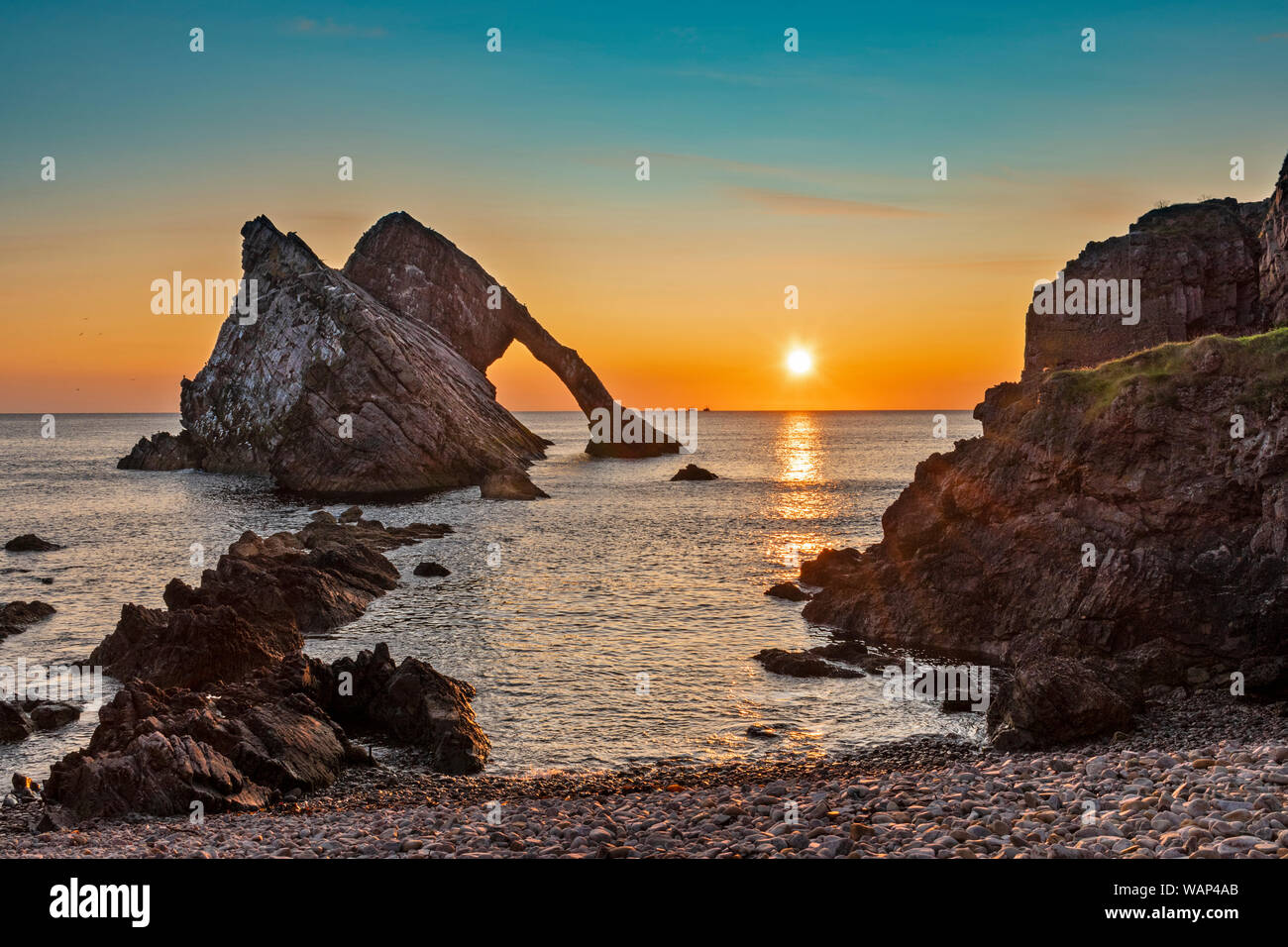 BOW FIDDLE ROCK PORTKNOCKIE MORAY COAST SCOTLAND COLOURFUL SUNRISE  AND TWO FISHING BOATS ON THE HORIZON SUMMER MID AUGUST Stock Photo