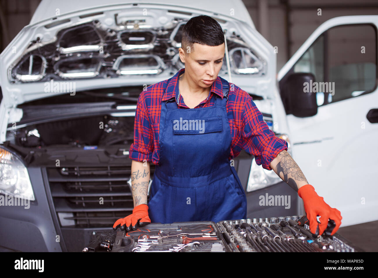 Woman works at the car repair checking whether she has all the instruments she could possibly need for her work. Stock Photo