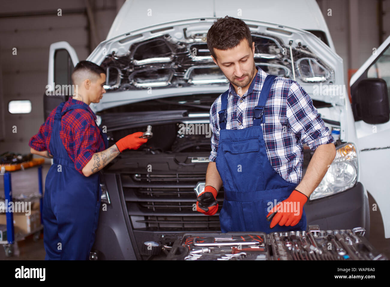 Two mechanics work under repairing a microbus before they get paid for it.. Stock Photo