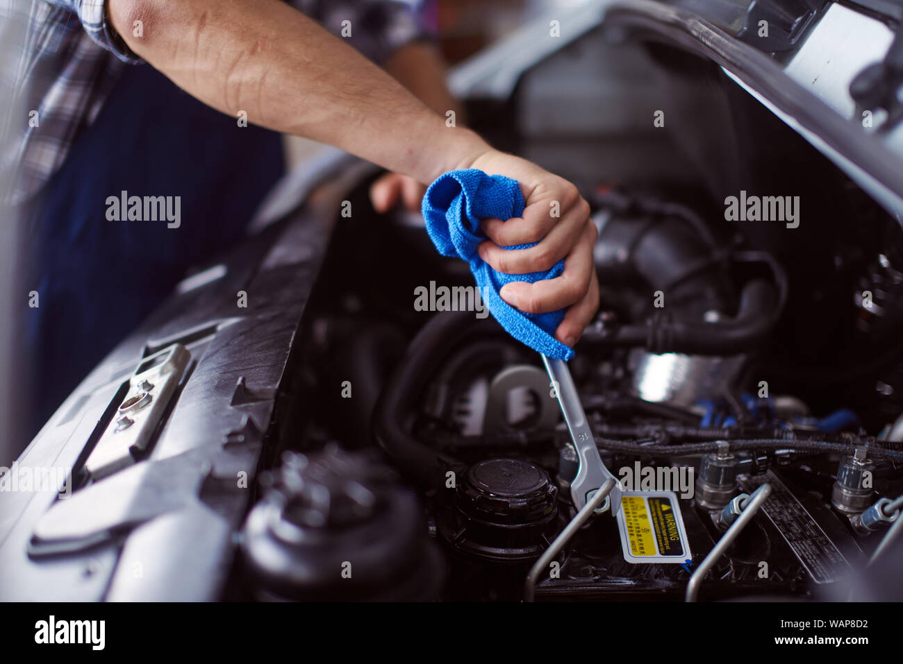 Close up of the working process in the car repair workshop done by a strong male with his equipment. Stock Photo