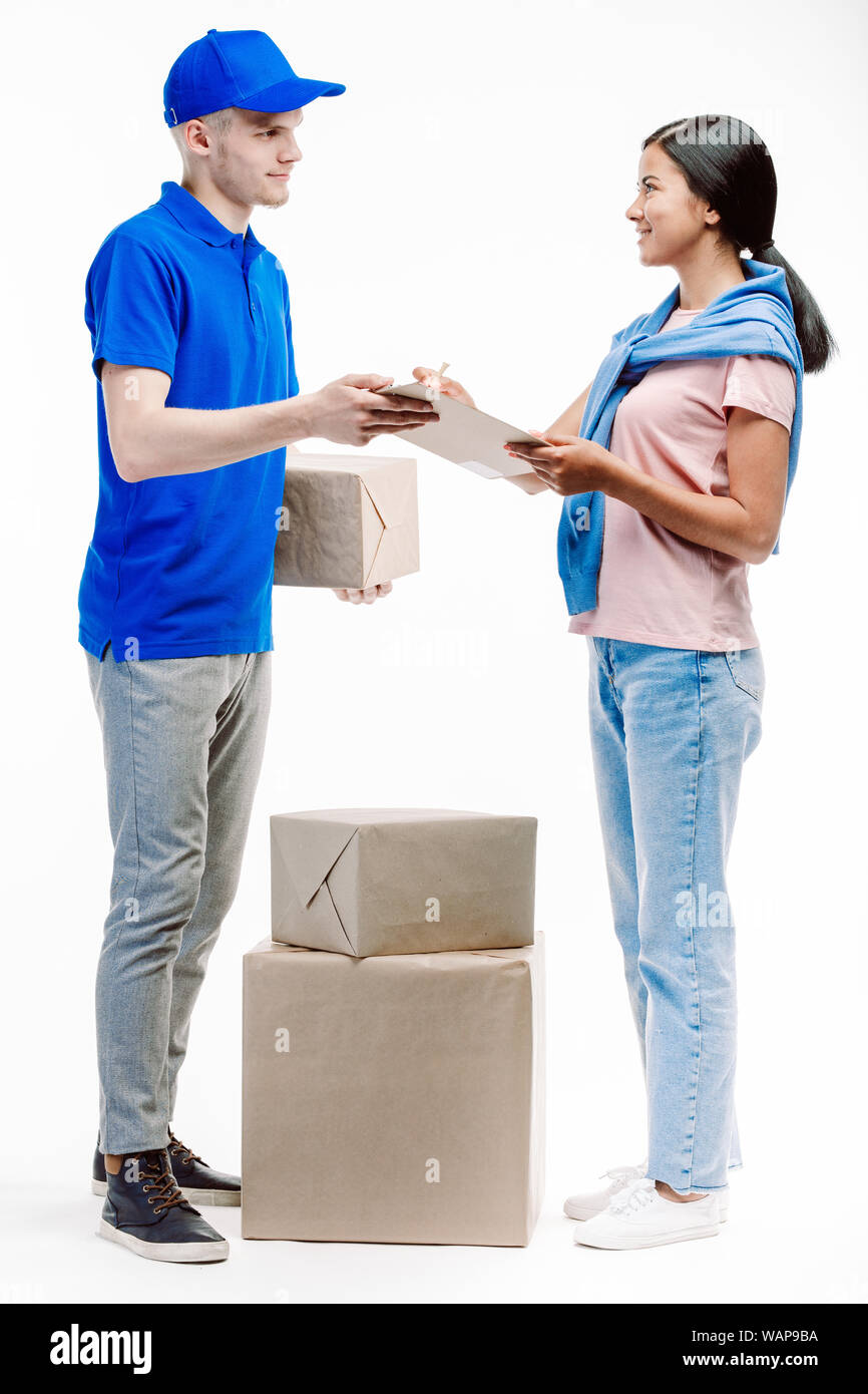 Postman delivers three big parcels to a client as she signes the delivery documents. Stock Photo