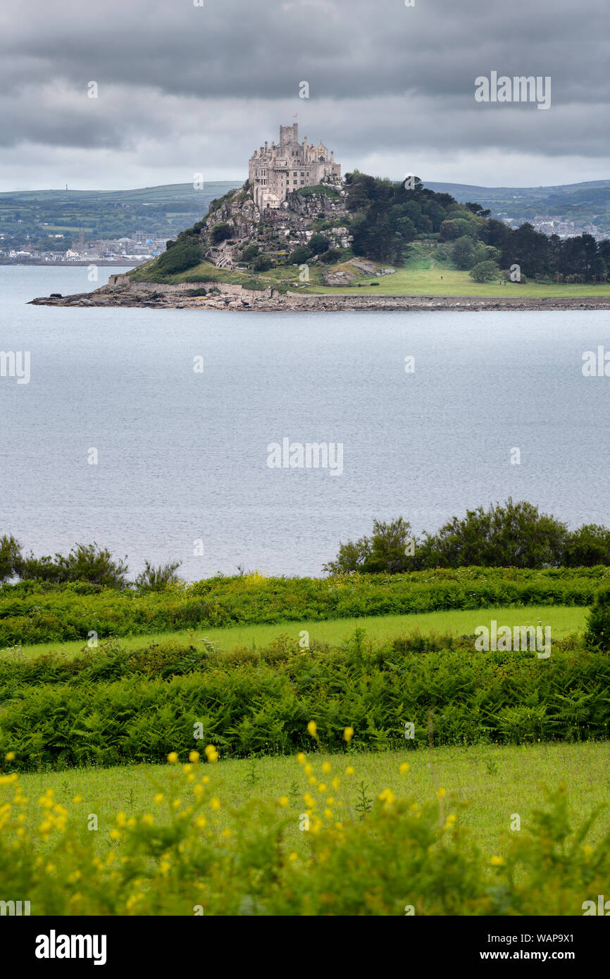 St Michael's Mount tidal island under cloudy skies in Mounts Bay from wild fields of Perranuthnoe Cornwall England Stock Photo