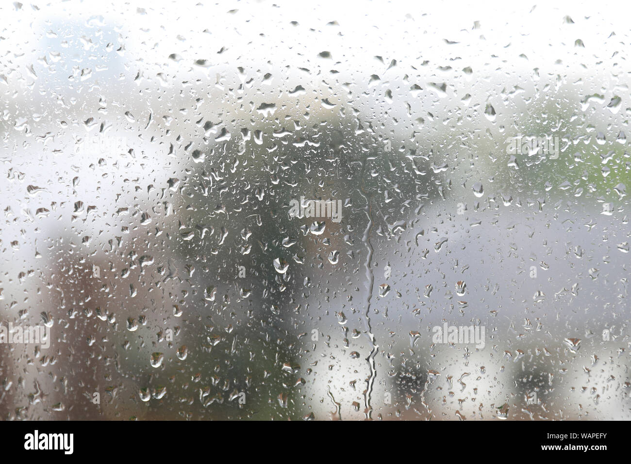 Rain drops trickling down a window in London, UK Stock Photo