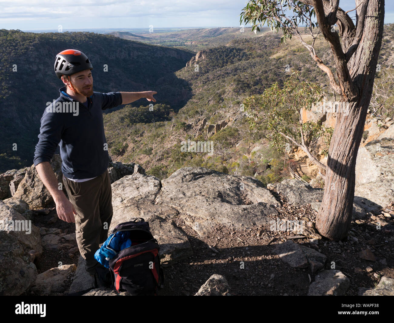 Technical climbing instructor pointing out rock face and entrance