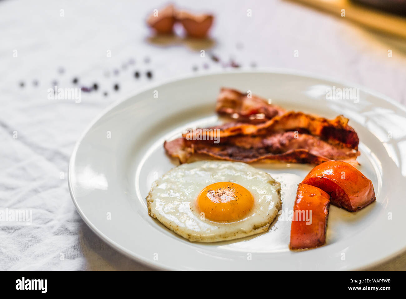 Fried chicken eggs with crispy bacon and tomatoes against white ...