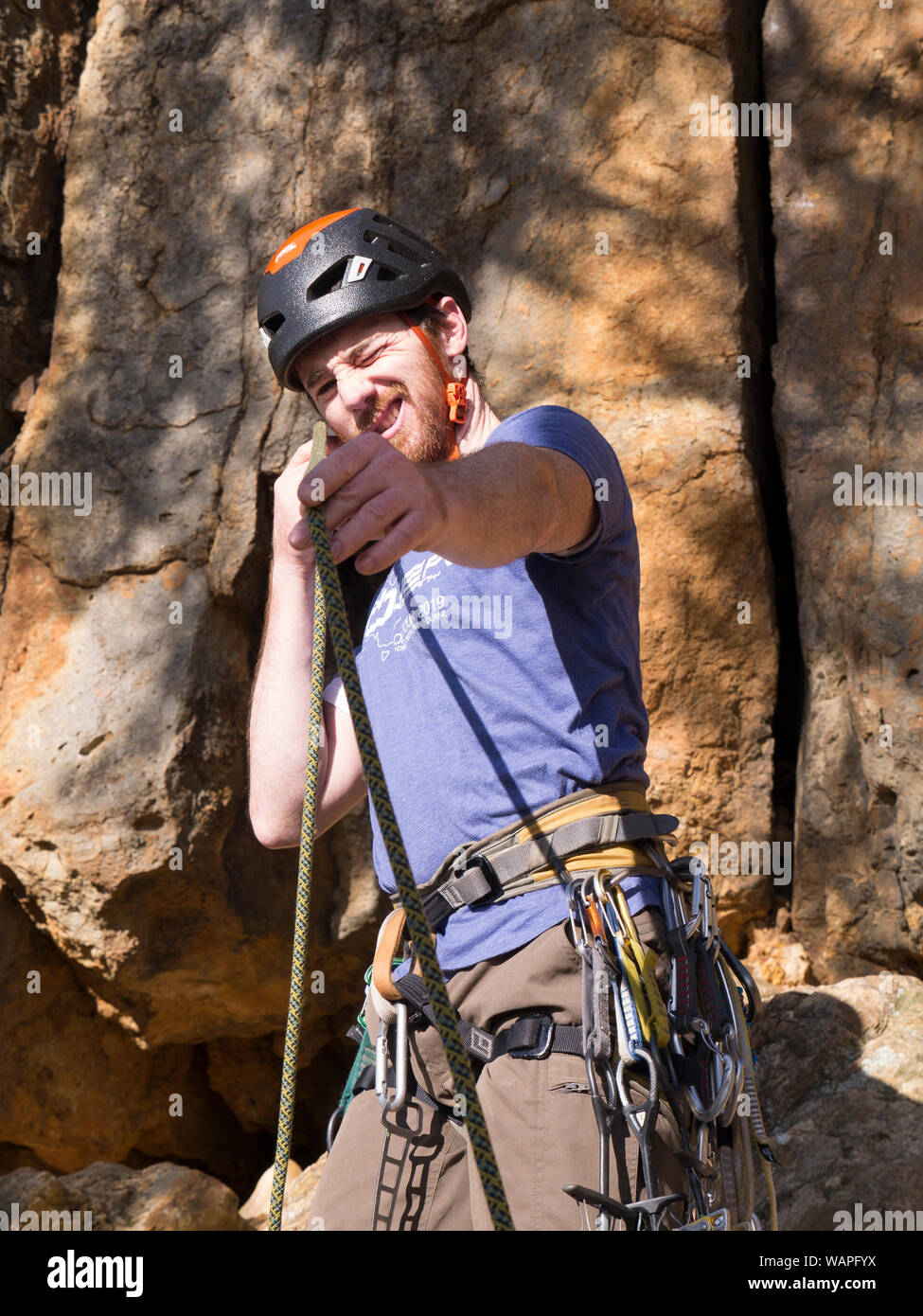 Technical climbing instructor inspecting rope by holding up to eye and
