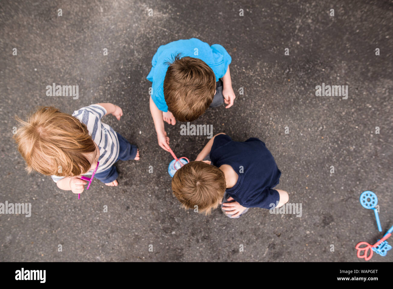 looking down on three boys playing outside with bubbles Stock Photo