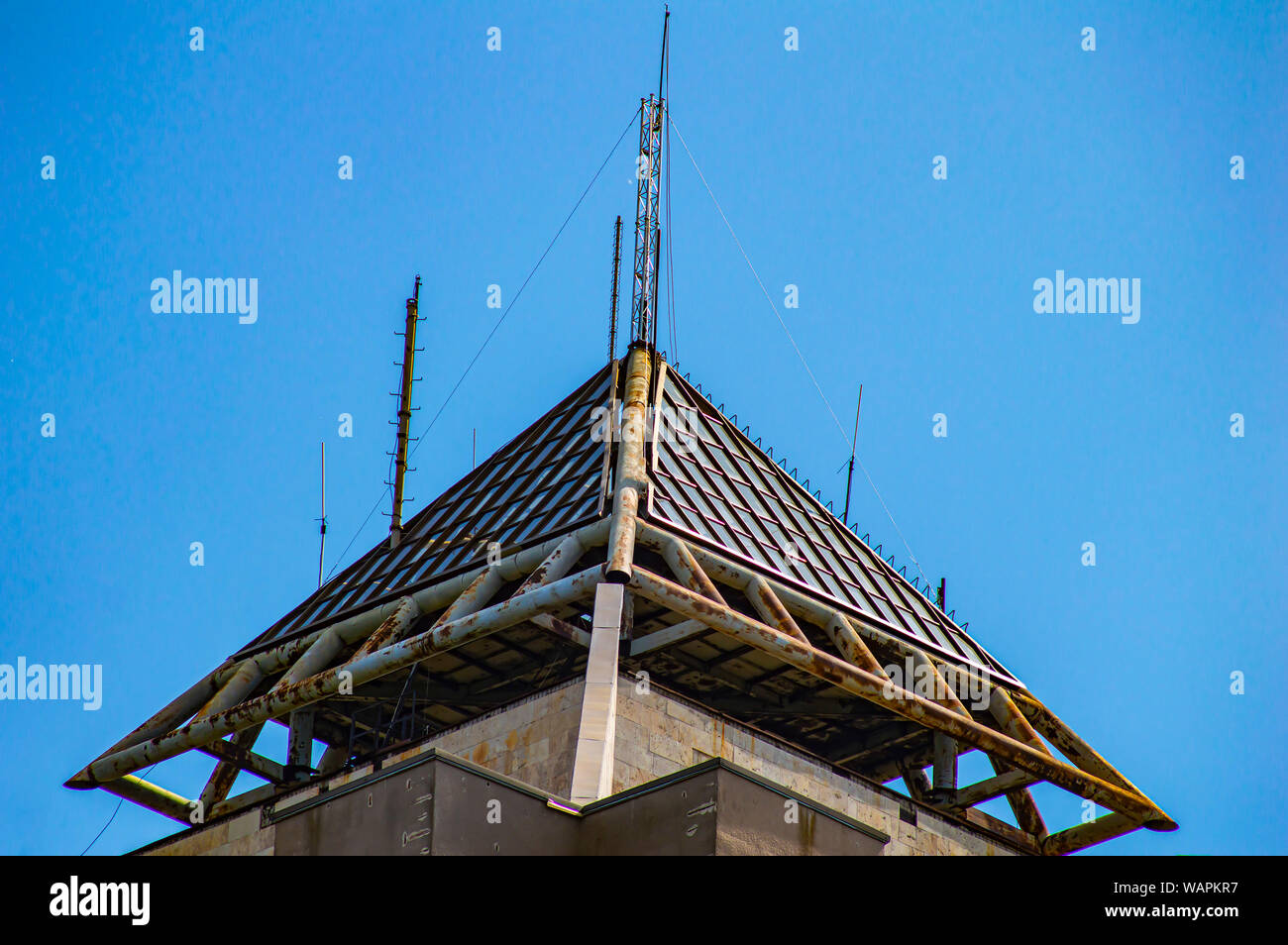 The pyramidal top of a tall building against the blue sky. Background ...