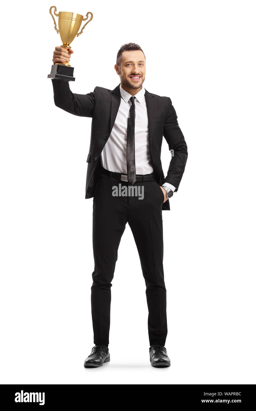 Full length portrait of a happy young man in a suit holding a golden trophy cup isolated on white background Stock Photo