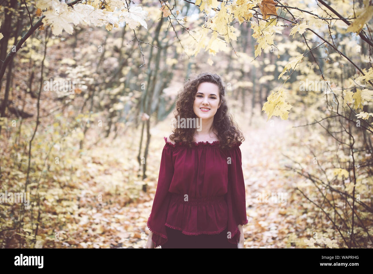 Beautiful Girl With Curly Dark Hair In A Maroon Top In An Autumn
