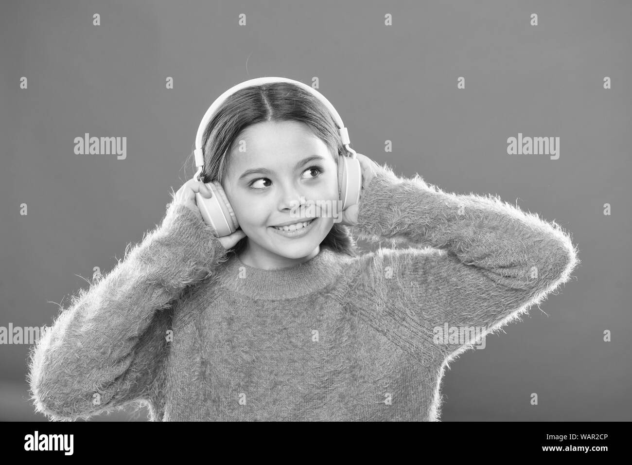 DJ, put the record on. Cute small child wearing DJ headphones. Little girl listening to music and dancing on silent disco in earphones. Adorable DJ girl. Enjoying music playing on DJ party. Stock Photo