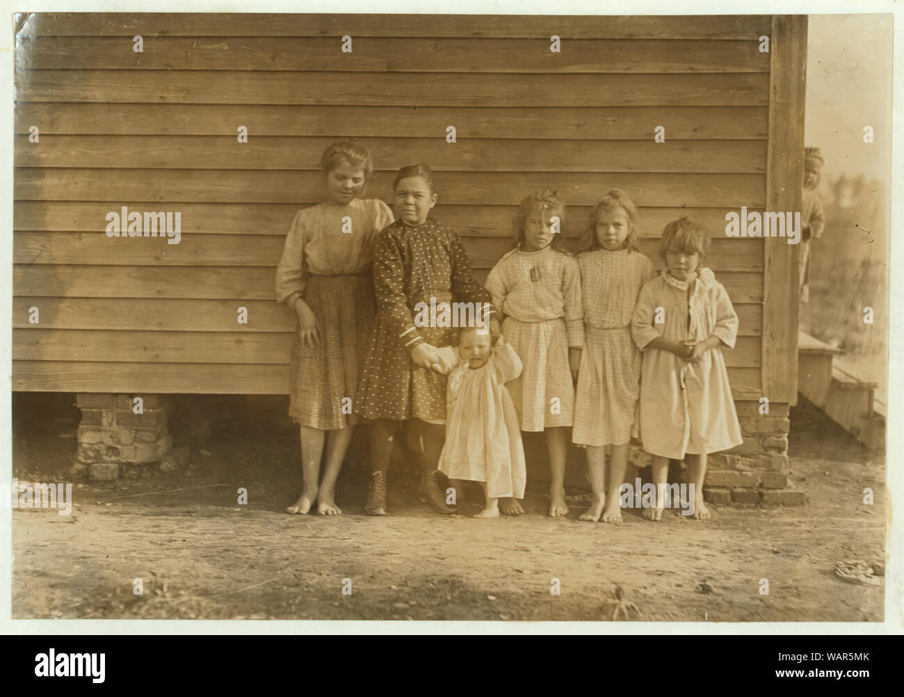 Dillon Mill (tallest) Lizzie McKenzie, Has helped 1/2 year. Mamie Baxley (holding baby). Been in mill 3 years. Runs 4 sides = 40 cents a day. Maud & Daisy help. Abstract: Photographs from the records of the National Child Labor Committee (U.S.) Stock Photo
