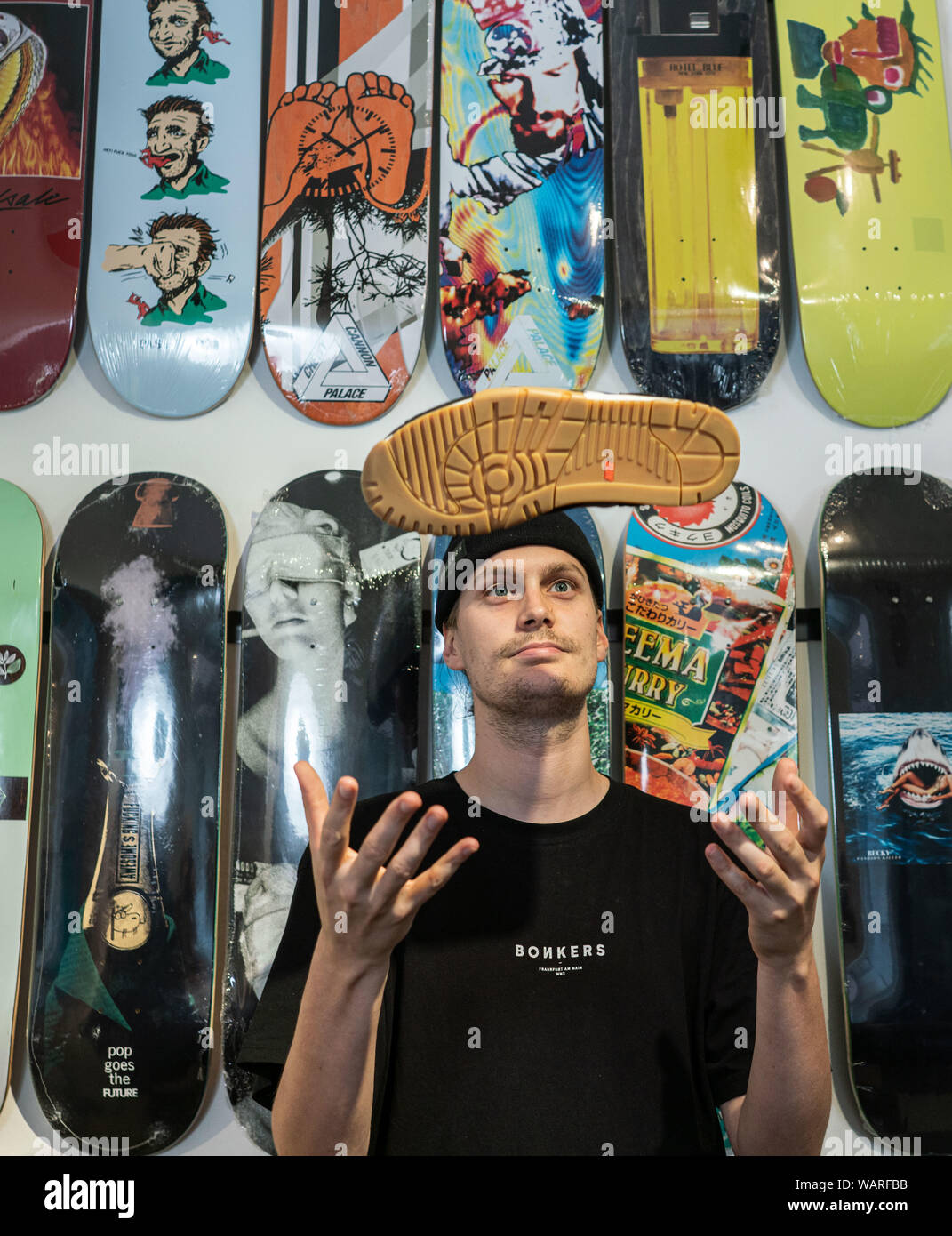 19 August 2019, Hessen, Frankfurt/Main: Martin Schreiber throws a shoe up  in his shop "Bonkers" in Sachsenhausen, where he sells skateboards, clothes  and sneakers. When selling sneakers in limited editions to collectors,