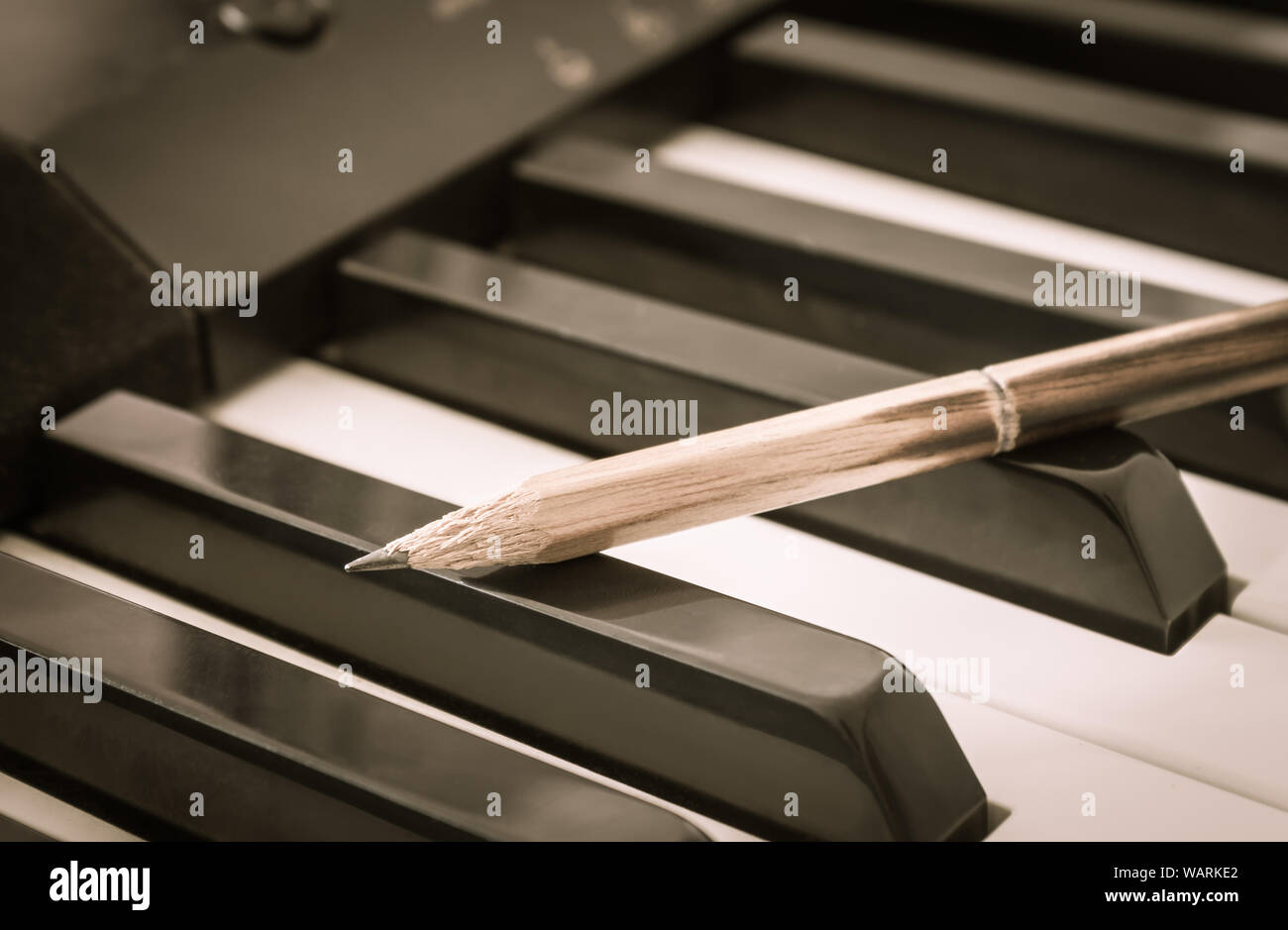 Old Pencil on Black Keys of Electric Piano in Crosswise View. Concept