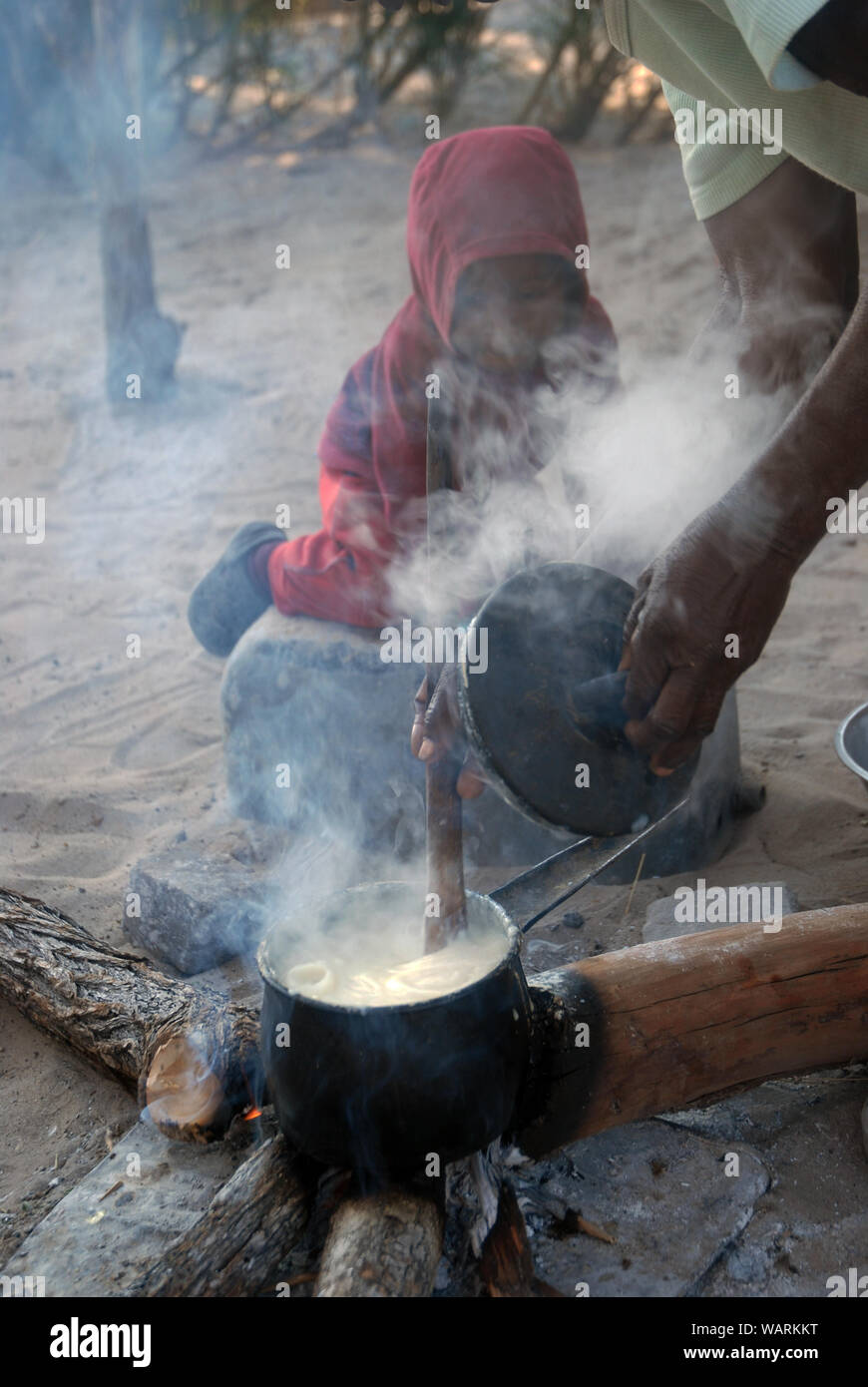 Old lady cooking a pot of Nshima, a thick porridge made from finely