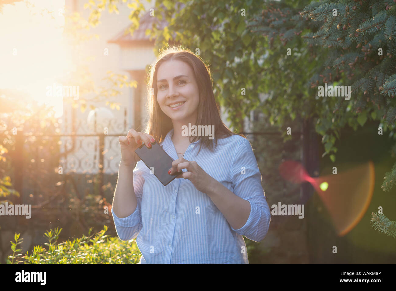 Girl is happy with her new smartphone. Emotional woman in the spring sunset Stock Photo