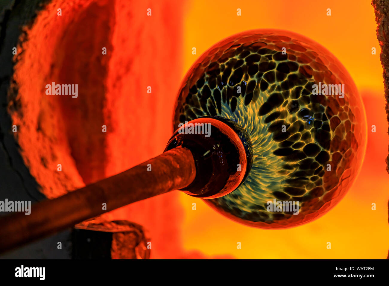 Glass blower manufacturing process, working on a bubble of melted glass