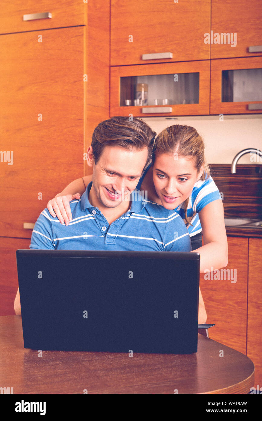 Couple having fun while surfing in internet. They're using laptop in home. Stock Photo