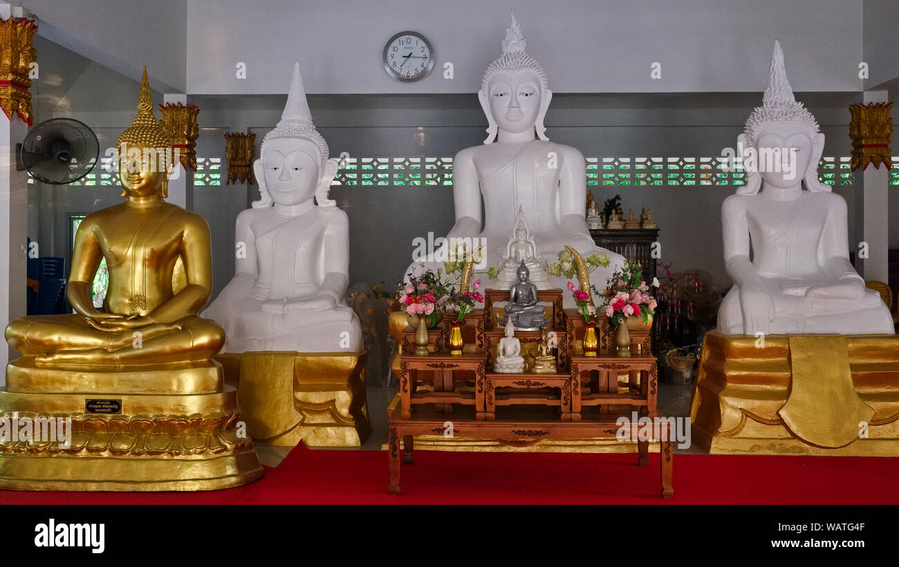 The three ancient (newly painted) white Buddha statues of Wat Phra Kao Gao, flanked by a newer golden Buddha statue, Thalang, Phuket Thailand Stock Photo