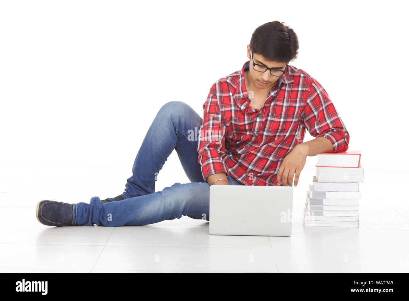 College student leaning on stack of books and using laptop Stock Photo ...