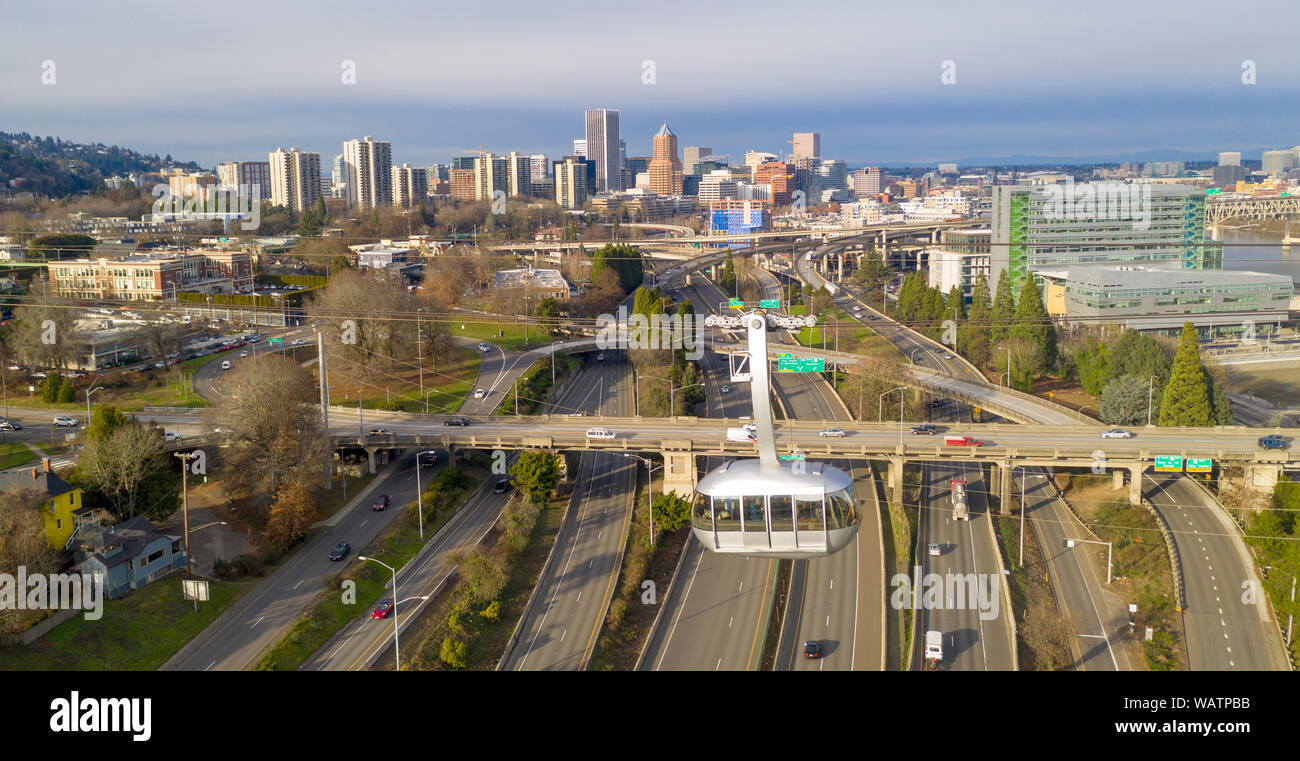 A shiny aerial tram car moves people over interstate 5 south of Portland Oregon Stock Photo