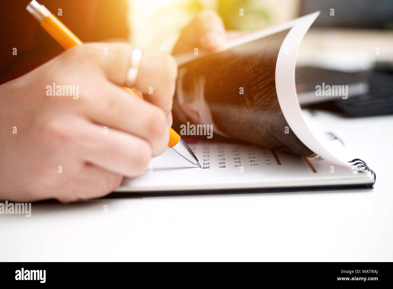 Picture of Man writing on notebook with pen and holding mobile in hand ...