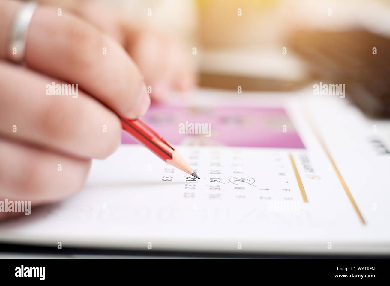 Picture of Man writing on notebook with pen and holding mobile in hand ...